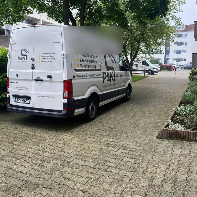 Geparkter Inspektionswagen von P&N Kanaltechnik zwischen Wohnblöcken